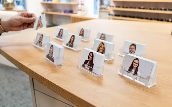 Visitenkarten mit Fotos von Mitarbeitern stehen in Haltern auf einem Holztresen im Büro.